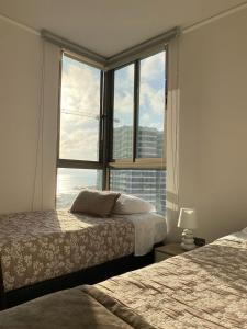 a bedroom with two beds and a large window at Exclusivo departamento tres dormitorios, capacidad 6 personas, excelente vista al mar para disfrutar de las puestas de sol in Antofagasta