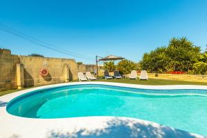 a swimming pool with two chairs and an umbrella at Nirvana Gozitan Villa & Pool - Happy Rentals in Qala +29 photos