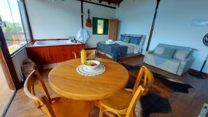 einen Holztisch mit Stühlen und eine Schale mit Obst darauf in der Unterkunft Chalé Luz do Luar Romantismo e uma linda vista in Campos do Jordão
