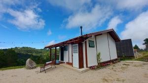 ein kleines Haus mit einer Bank im Sand in der Unterkunft Chalé Luz do Luar Romantismo e uma linda vista in Campos do Jordão