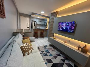 a living room with a couch and a tv on a wall at Perfeito Ap Caruaru in Caruaru