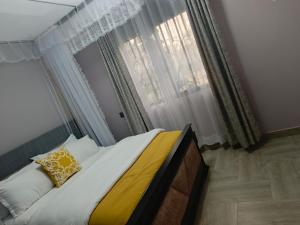 a bedroom with a bed and a window with curtains at Nsuube Apartment in Mukono