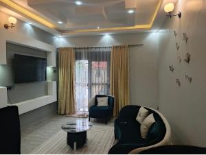 a living room with a couch and chairs and a tv at Nsuube Apartment in Mukono