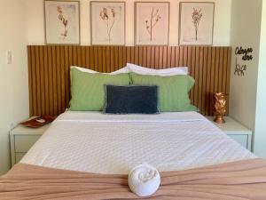 una camera da letto con un grande letto bianco con cuscini verdi di Casa Trindade - Residencial Caminho da Praia a Porto Seguro