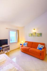 a living room with an orange couch and a television at Cá Stella studio Flat in Riomaggiore