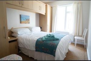 a bedroom with a bed and a chair and a window at Portrush Seaview Beach House in Portrush