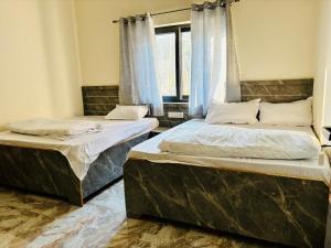 two beds sitting in a room with a window at Juyal palace in Jāmb