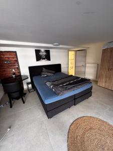 a bedroom with a bed with a blue bedspread and a table at Stadt Apartments Bade in Rosenheim