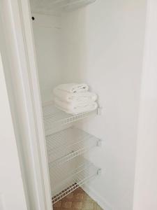 un armario con toallas blancas en los estantes en Excellence vacation home, en St. John's