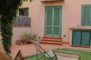 a patio with chairs and a house with green shutters at Il Glicine in Livorno