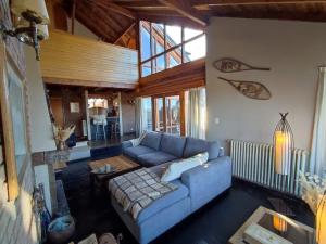 Una sala de estar con un sofá azul y una mesa. en Casa Suiza, vistas panorámicas al lago, ciudad y montañas !!, en San Carlos de Bariloche