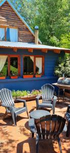 two chairs and a table in front of a house at cabaña azul in Trevelín