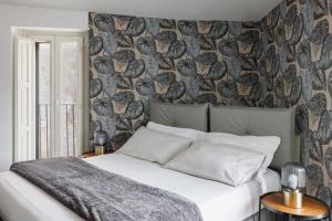 a bedroom with a bed and a wall with birds wallpaper at Casa Dona - Essenza in Catania