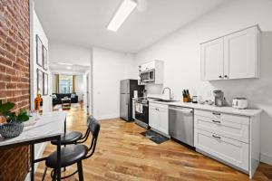 Una cocina con gabinetes blancos y una mesa con sillas. en Cozy 1st-Floor Flat 2BR Backyard Free Parking, en Louisville