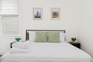 1 dormitorio blanco con 1 cama blanca grande con almohadas verdes en Cozy 1st-Floor Flat 2BR Backyard Free Parking, en Louisville