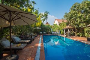 a swimming pool with chairs and an umbrella at Sonalong Boutique Village & Resort in Siem Reap