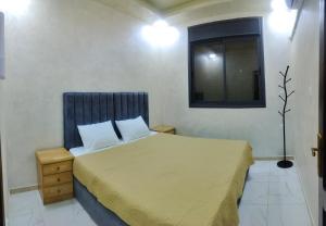 a bedroom with a bed with a yellow blanket and a window at Furnished apartments for rent 1 in Aqaba