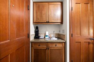 a small kitchen with wooden cabinets and a sink at Everline Resort & Spa Palisades- Forest View no resort fee in Olympic Valley