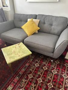 a gray couch with a yellow pillow and a coffee table at Cosy Room in Flat - Central Location in London