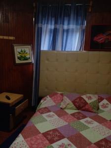 una camera da letto con un letto con una trapunta sopra di Hostal Palmera a Rancagua