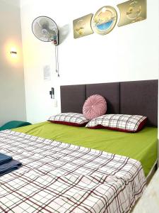 a bedroom with a bed with green sheets and a fan at Nhà Nghỉ Hưng Hà in Kon Rung (1) +20 photos