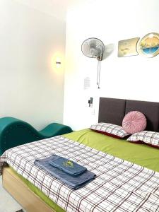 a bedroom with a bed with a blanket and a fan at Nhà Nghỉ Hưng Hà in Kon Rung (1)