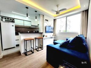 a living room with a blue couch and a kitchen at Xingu Reserva Ipanema in Porto Alegre