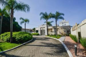 une allée avec des palmiers en face d'un bâtiment dans l'établissement Xingu Reserva Ipanema, à Porto Alegre