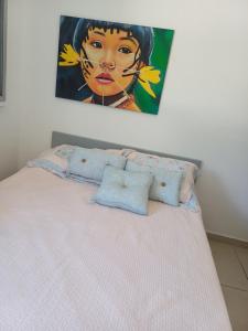 a painting of a girl is above a bed at VISTA DESLUMBRANTE APTO 709 in Ubatuba
