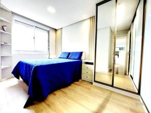 une chambre avec un lit bleu et un grand miroir dans l'établissement Xingu Reserva Ipanema, à Porto Alegre