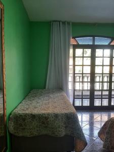 a green bedroom with a bed in a room with windows at Casa em Mangaratiba RJ - 40 metros da Praia in Mangaratiba