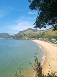 a beach with people swimming in the water at Casa em Mangaratiba RJ - 40 metros da Praia in Mangaratiba