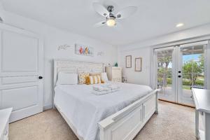 a white bedroom with a bed and a ceiling fan at Sandy Gull Too in Orange Beach