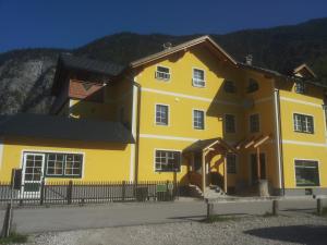 a yellow house with a fence in front of it at Haus Bellevue in Obertraun