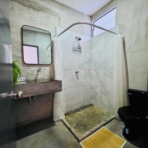a bathroom with a shower with a sink and a mirror at Vibes Wellness House in Tamanique