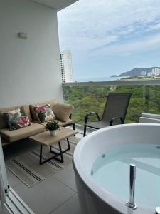 a bathroom with a tub and a couch and a chair at Aparta Suite con vista al mar in Santa Marta