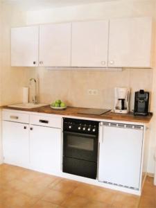 a kitchen with white cabinets and a black oven at Haus an der Therme in Bad Endorf