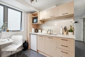 a kitchen with white cabinets and a sink and a window at Cityscape on White - Auckland Central Studio in Auckland +3 photos