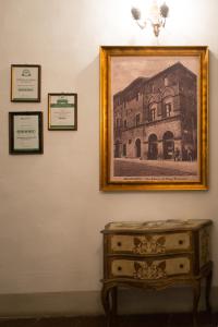 a painting of a building on a wall with a dresser at Residenza D'Epoca Palazzo Buonaccorsi in San Gimignano