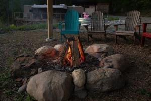 a fire pit with rocks and a table and chairs at Conesus Lake Glamping With A View in Conesus