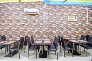 a row of tables and chairs in front of a brick wall at Hotel O New Orchid Inn in Kolkata