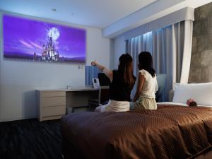Due donne sedute su un letto in una camera d'albergo di J Hotel Rinku a Tokoname