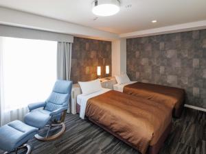 una camera d'albergo con due letti e una sedia blu di J Hotel Rinku a Tokoname