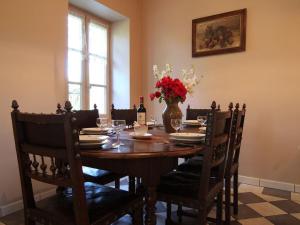 a dining room table with chairs and a vase of flowers at Maison de charme avec grand parc pour des vacances en famille au cœur de l'Auvergne - FR-1-582-278 in Bournoncle-Saint-Pierre