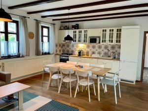 a kitchen with a wooden table and white chairs at Chalupa - Vinařství Popela in Perná