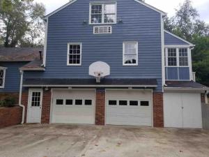 a blue house with two garage doors and a basketball hoop at The House on the Hill - Year Round Rental in Augusta