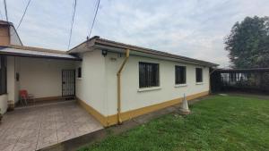 una piccola casa bianca con un prato di Amplia casa 7 personas 2 cocheras a Temuco