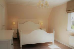 a bedroom with a white bed and a window at Summer Dream in De Haan