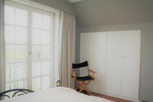 a bedroom with a bed and a window and a chair at Albatros D2 in De Haan