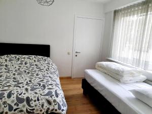 a white bedroom with a bed and a window at Les Bruyeres in De Haan